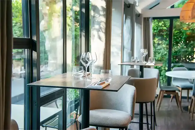 Photo de l'intérieur du restaurant : des tables hautes pour deux personnes. Les chaises sont beiges