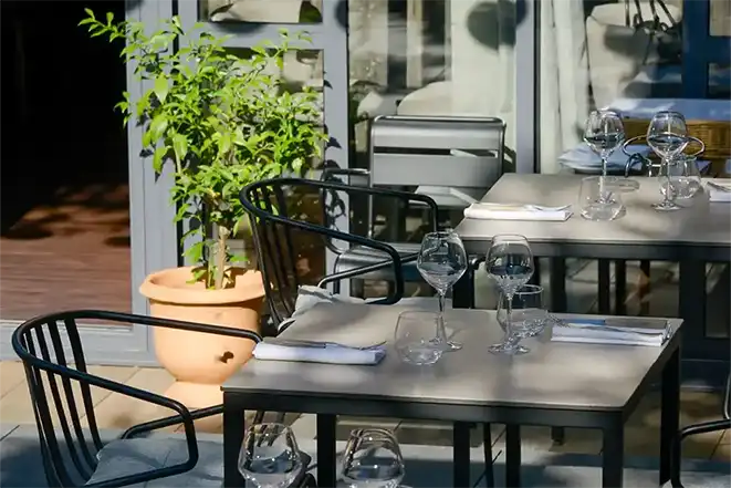 Photo de la terrasse ombragée du restaurant, mobilier métallique gris clair et foncé